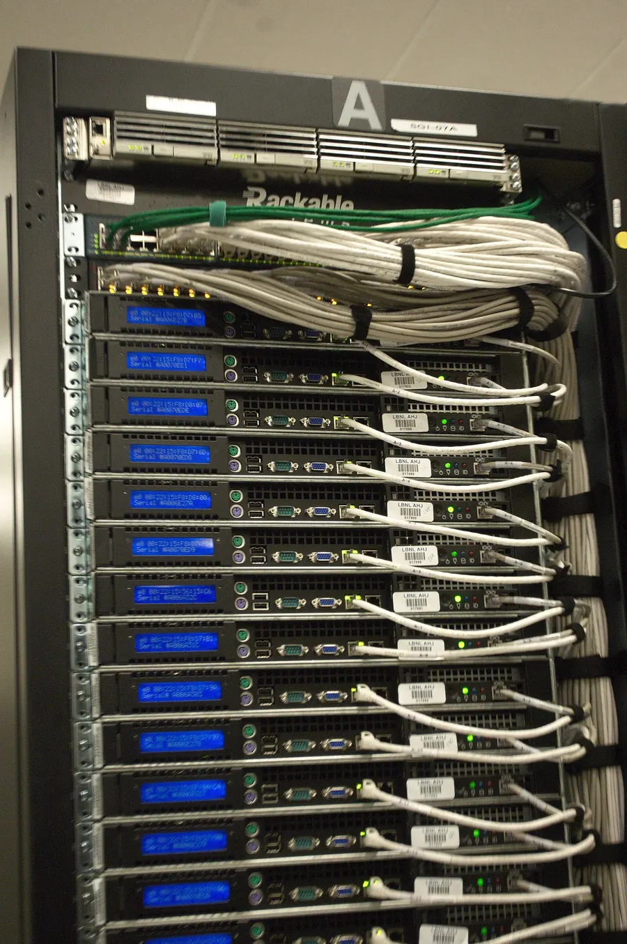 A close view of cables plugged into the back of a computer rack.