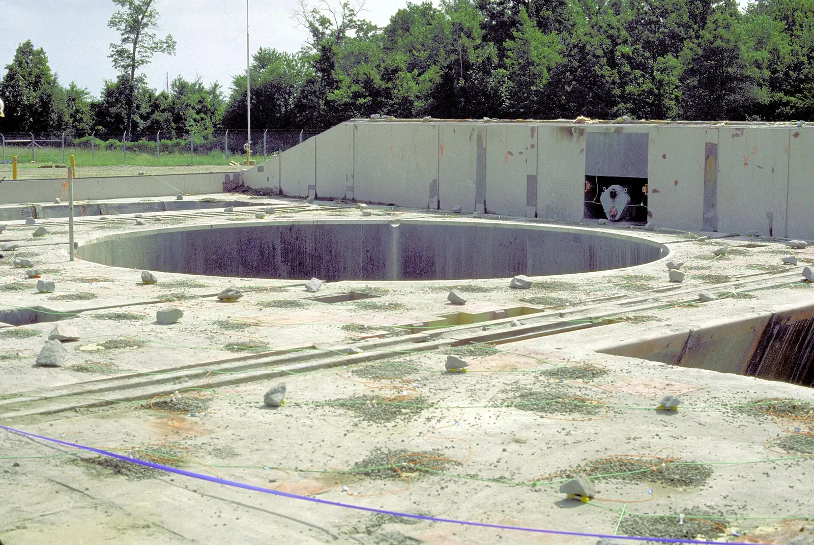 A Cold War missile silo with a large circular opening and concrete walls, set in grass.